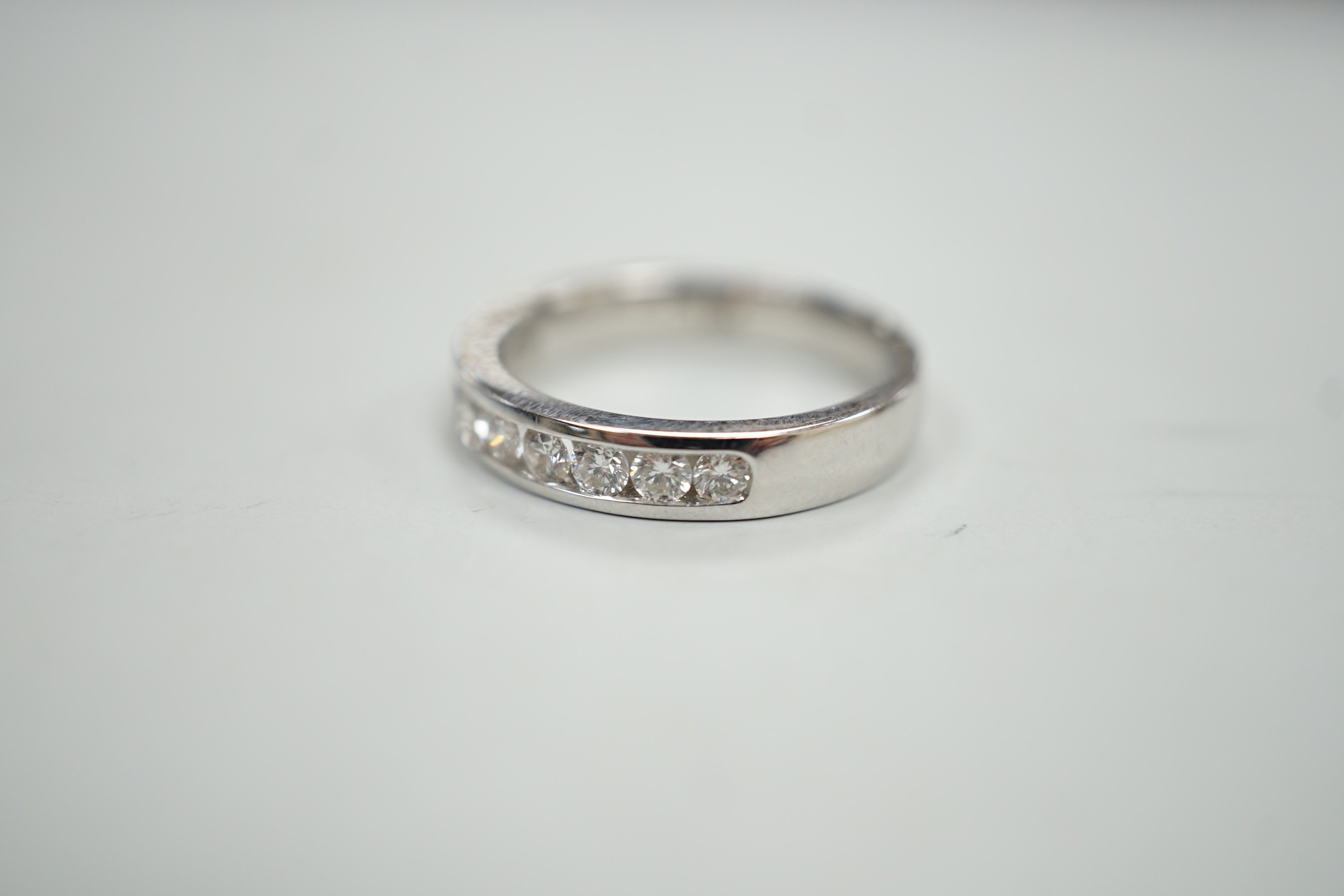 A modern 18k white metal and ten stone channel set diamond half eternity ring, size L/M, gross weight 4.1 grams.